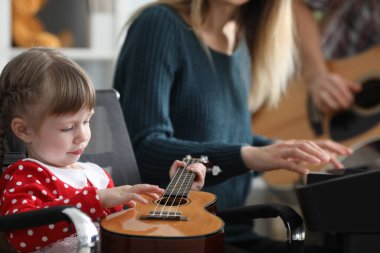 Ebeveynler bebeğe birlikte gitar çalmayı öğretir.