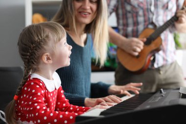 Ebeveynler kızlarına müzik aletleri çalmayı öğretiyor.