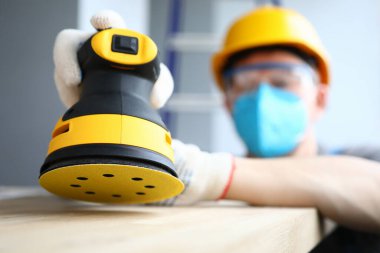 Maskeli müteahhit zımpara ahşap yüzeyi parlatıyor