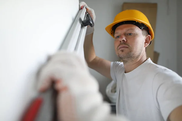 Construtor capacete mede nível de parede com a construção — Fotografia de Stock