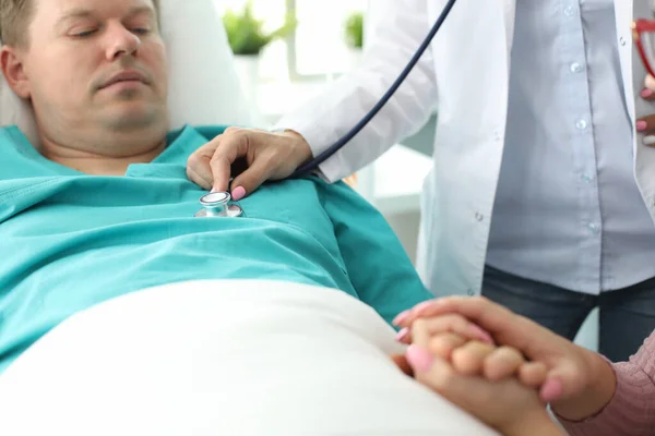 Homem doente deita-se na cama na clínica, médico examina — Fotografia de Stock