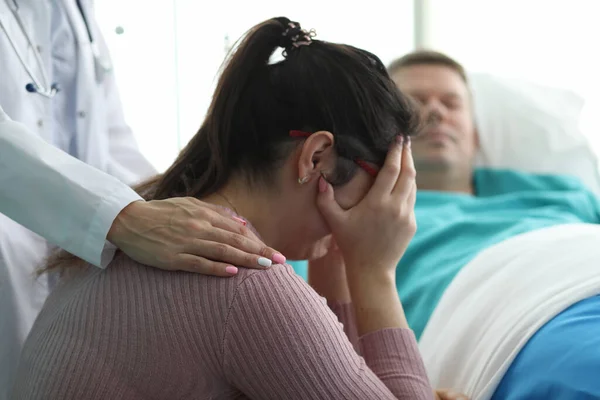 Žena na klinice pláče poblíž muže na nemocničním lůžku — Stock fotografie