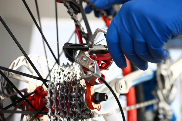 Ręka naprawiacza rękawic reguluje narzędzie na rowerze — Zdjęcie stockowe