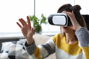 Kız evde oturup sanal gözlüklere bakıyor.