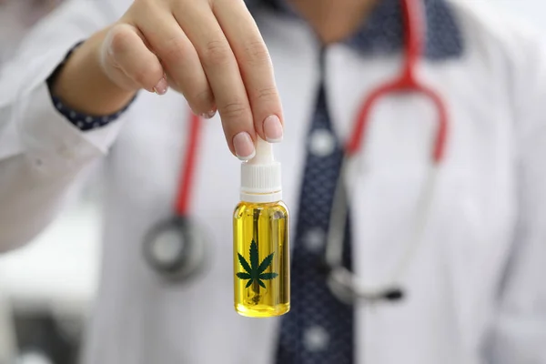 Läkare med stetoskop håller flaska hampa olja — Stockfoto