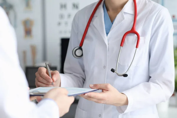 Ärztin signiert Patientenkarte mit Diagnose — Stockfoto