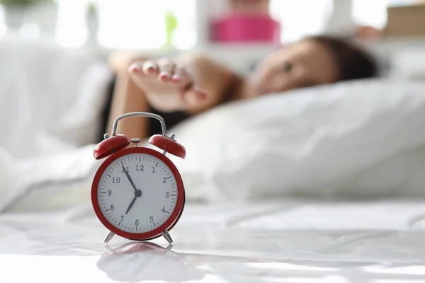 Girl lies on bed and turns off alarm in morning — Stock Photo, Image