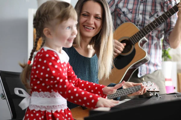 Os pais tocam guitarras, filha no sintetizador — Fotografia de Stock