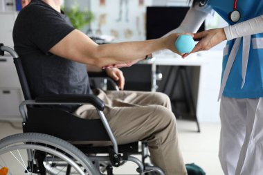Kadın hemşire engelli hasta rehabilitasyonu için dambıl kaldırmaya yardım ediyor.