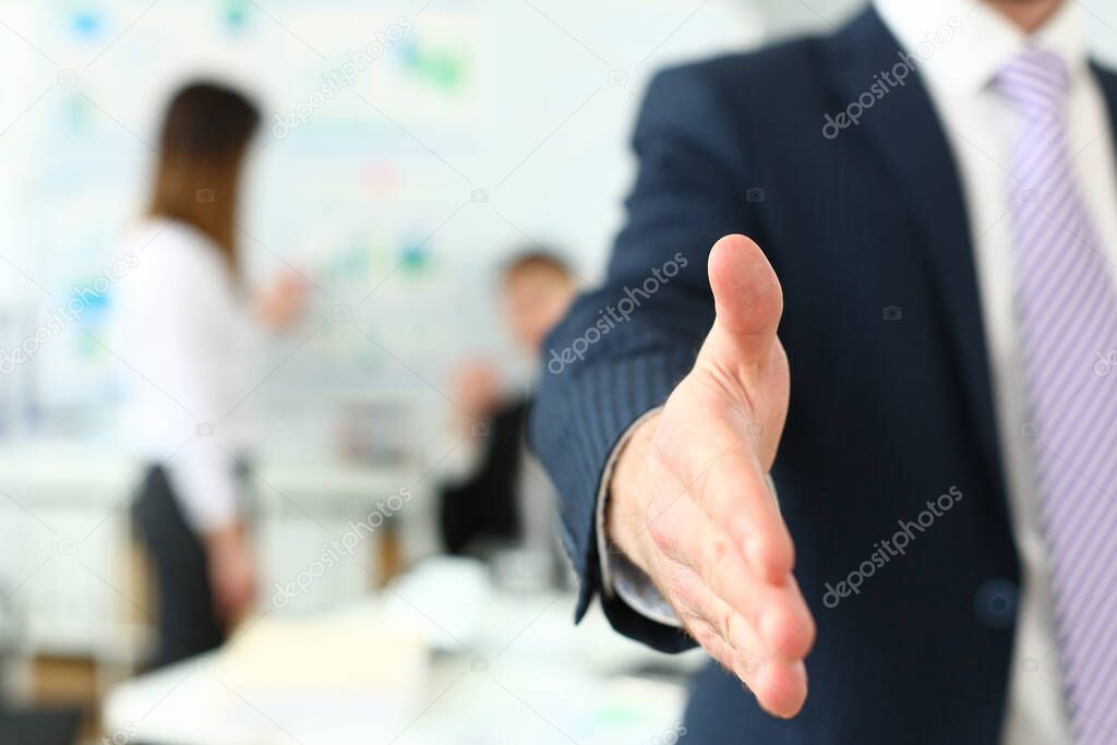 Businessman in suit and tie offering hand to shake to visitor