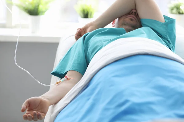 Нешалений чоловік лежить лікарняне ліжко під крапельницею — стокове фото