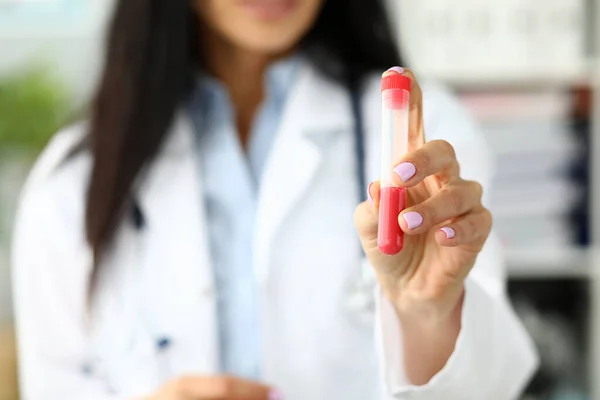 Женщина-врач держит пластиковую пробирку, содержащую красную жидкость — стоковое фото