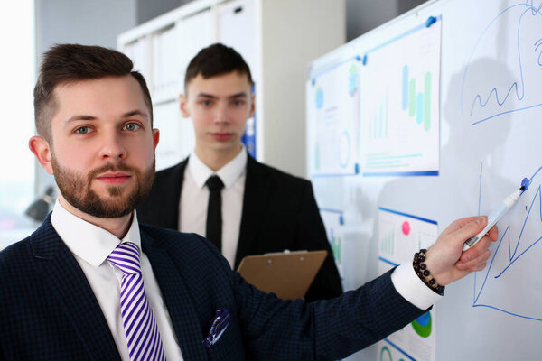 Улыбающийся красивый бородатый кавказский мужчина в офисе говорит что-то важное
