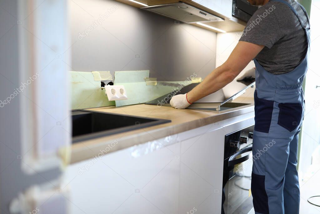 Repairman installs hob kitchen table in apartment