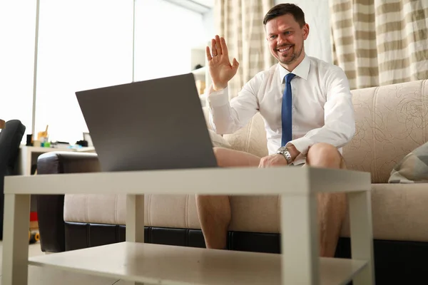 Man without trousers sits in front laptop at home