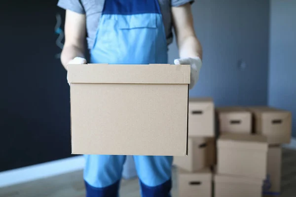 Man in work clothes is standing in office with box — Stock Photo, Image