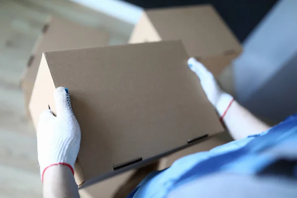 Крупный план погрузчика в перчатках держит картонную коробку — стоковое фото