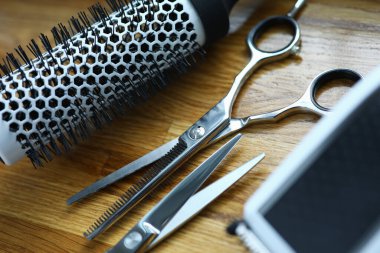 Kırpıcı ve tarak kuaförde, ahşap masanın üzerinde yatıyor.