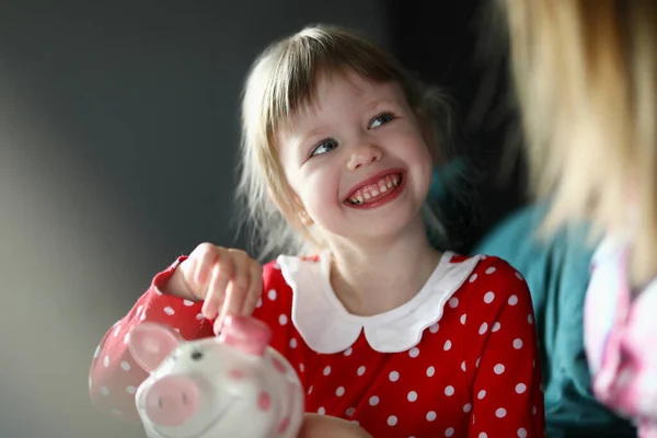 Gelukkig klein meisje in rode jurk houden zilveren munt in de hand — Stockfoto