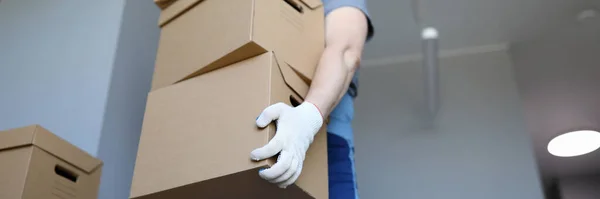 Man work clothes and gloves carries cardboard boxes — Stock Photo, Image