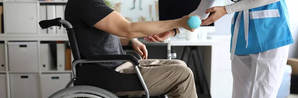 Доктор допомагає людині на інвалідному візку тримати гантель — стокове фото