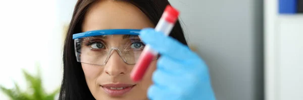 Hermosa mujer con gafas protectoras sosteniendo tubo de prueba —  Fotos de Stock