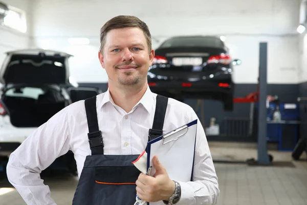 Man in uniform is standing at car wash with folder