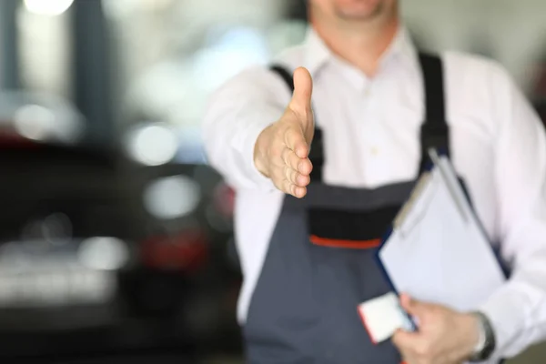 Car dealership male employee holds out his hand — Stock Photo, Image