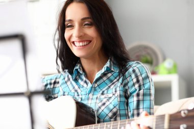Güzel bir kadın evde gitar çalar ve güler.