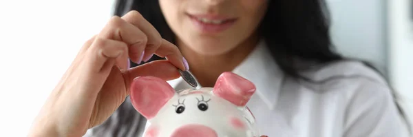 Miła dziewczyna umieszcza monetę w ceramicznej figurce świni — Zdjęcie stockowe