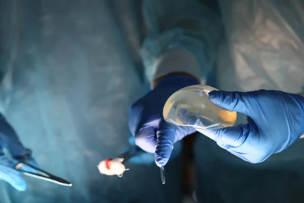 Surgeons hands holding breast implants and tools — Stock Photo, Image