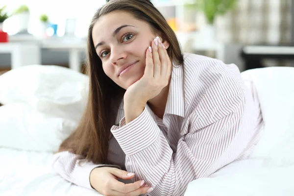 A casa sul letto giace allegra ragazza in pigiama — Foto Stock