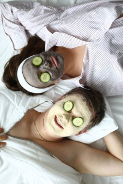 Couple lying on bed with cosmetic mask on face clipart
