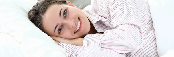 Ragazza felice in pigiama si trova sul letto e sorride — Foto Stock