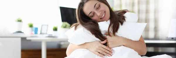 Chica sentada en la cama abrazando almohada y manta —  Fotos de Stock