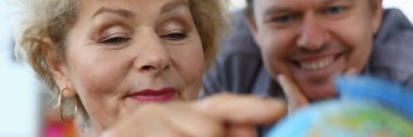 Elderly mother shows an adult son location globe