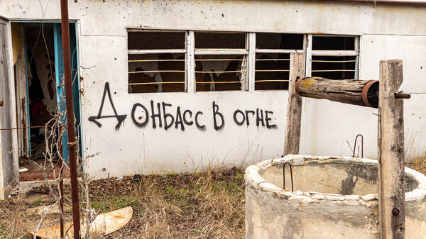 Vodyane, Donetsk region, Ukraine - December 2 2019: Destroyed and abandoned house on the front line with the words "Donbass on fire"