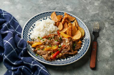 Peru yemeği Lomo saltado, kırmızı soğanlı sığır filetosu, sarı biber, domates, patates kızartması ve pilav. Boşluğu kopyala