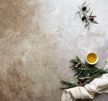 Zeytin dalı, peçete ve tabak, bıçak ve çatal bıçak, beton arka planda zeytinyağı