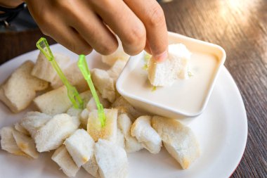 Adet ekmek daldırma tutan eller ve sos pandan yaprakları.