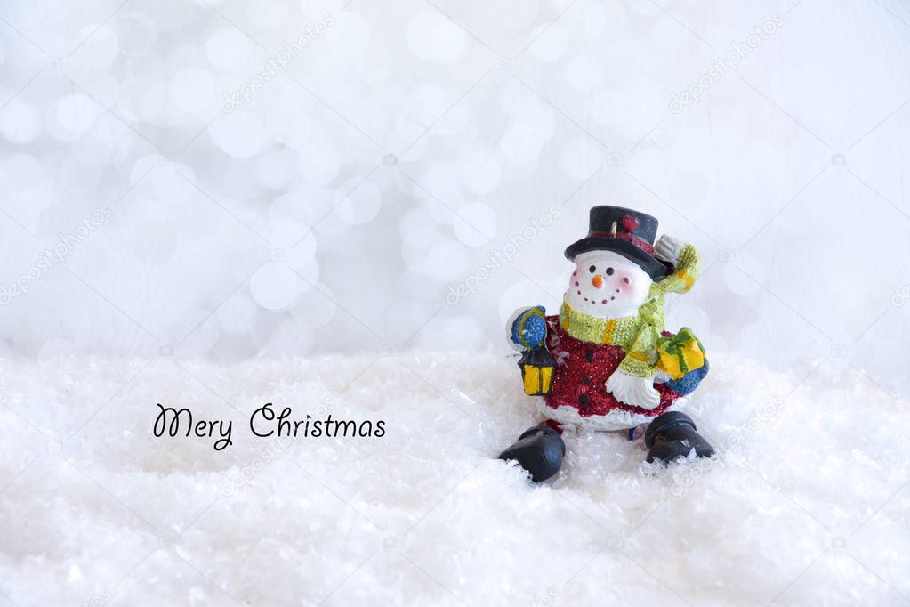Christmas card snowman sitting on the snow on a white luminous background.