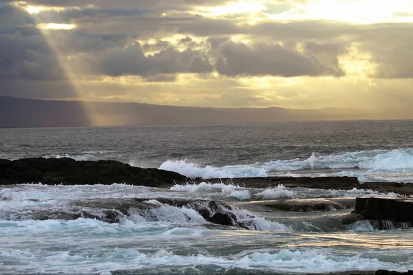 Raios de luz dançam sobre ondas batendo Fotografia De Stock