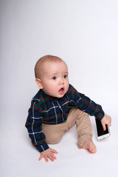 a small boy is smiling and holding a smartphone on a white background