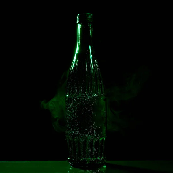黑色底座上有矿泉水的绿色瓶子 — 图库照片