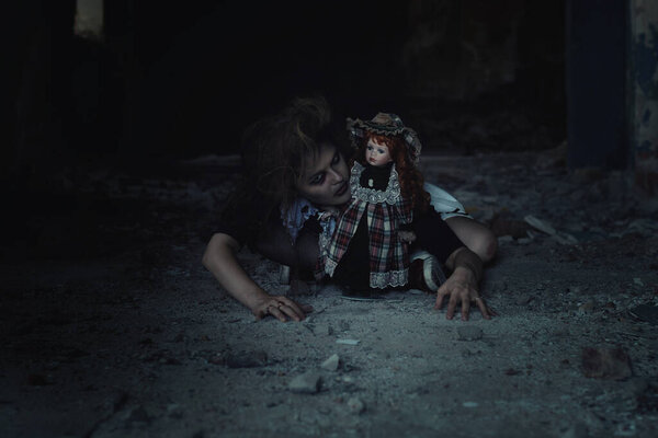 scary girl with a doll in an abandoned house