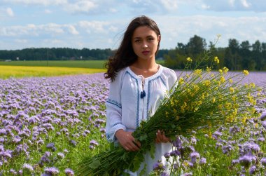 Çiçek tarlasında beyaz elbiseli genç bir kız. Tarlada çiçekli yaz tarlaları.