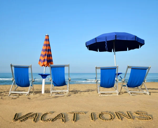 Ligstoelen en parasols aan een zandstrand. — Stockfoto