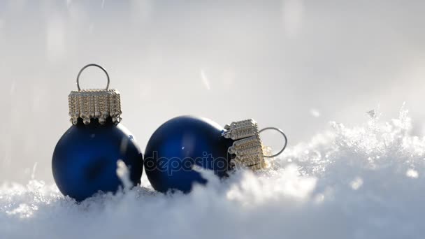 Schneefall auf zwei blauen Weihnachtsdekorationen. — Stockvideo