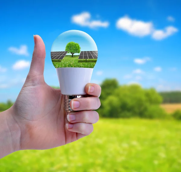 Hand mit erhobenem Daumen hält eine Öko-LED-Glühbirne mit Solarmodul. — Stockfoto