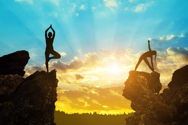 Silueta de una chica haciendo yoga sobre una roca — Foto de Stock